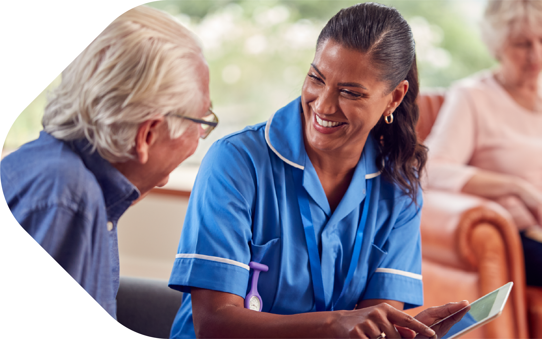 A nurse talking to a patient showing them information on tablet device