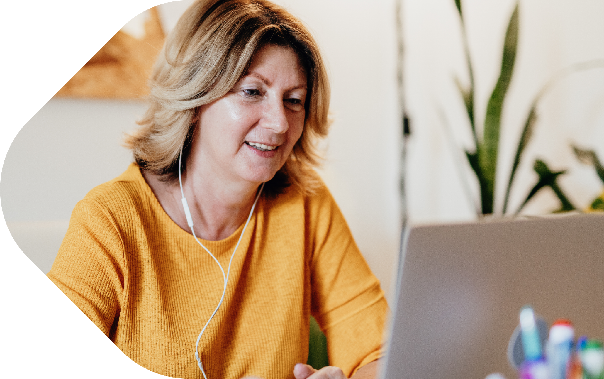 Woman with headphones in, looking at laptop screen
