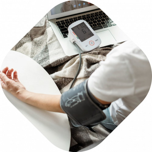 Patient with digital blood pressure machine, talking to healthcare professional on laptop